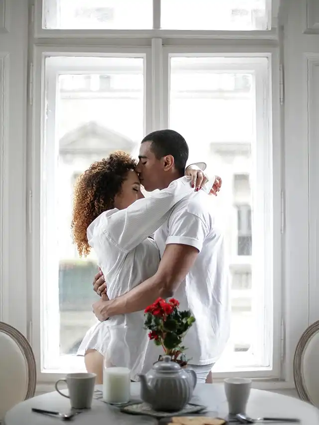 Pareja abrazándose con ternura en casa tras una reconciliación, problemas de pareja