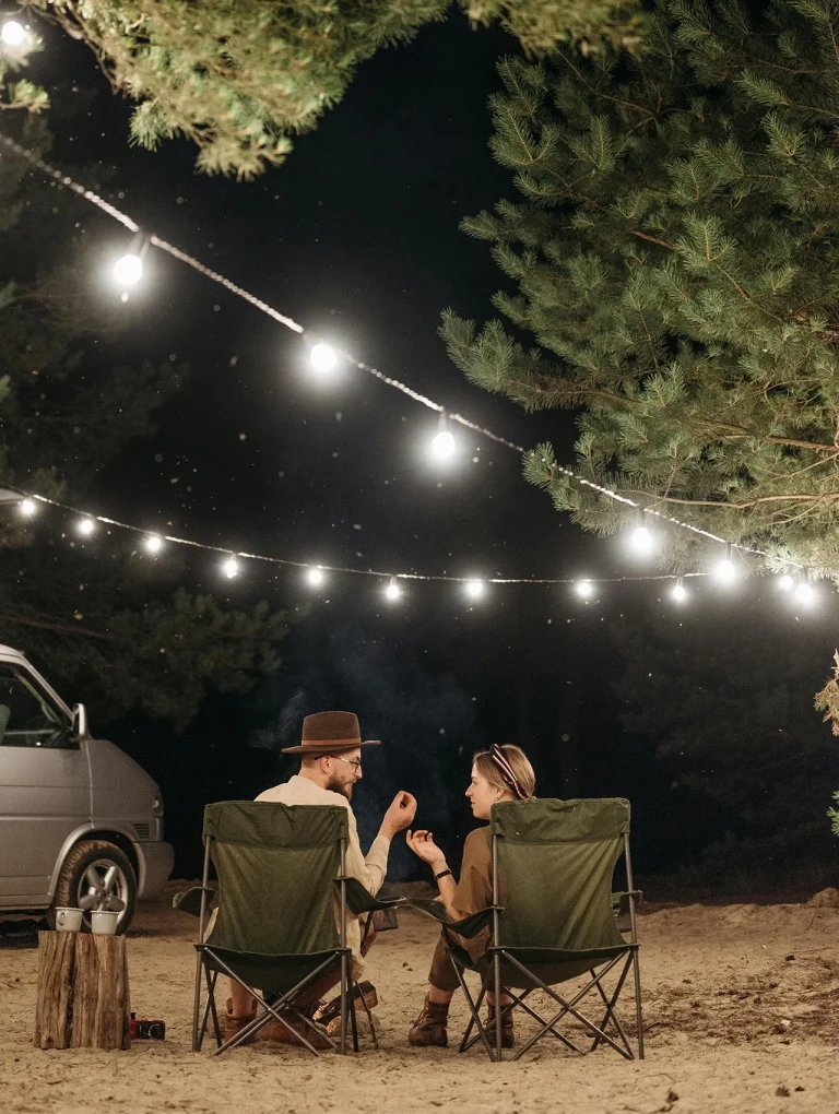 Pareja conversando de noche en campamento bajo luces, ejemplo de comunicación efectiva y asertiva.
