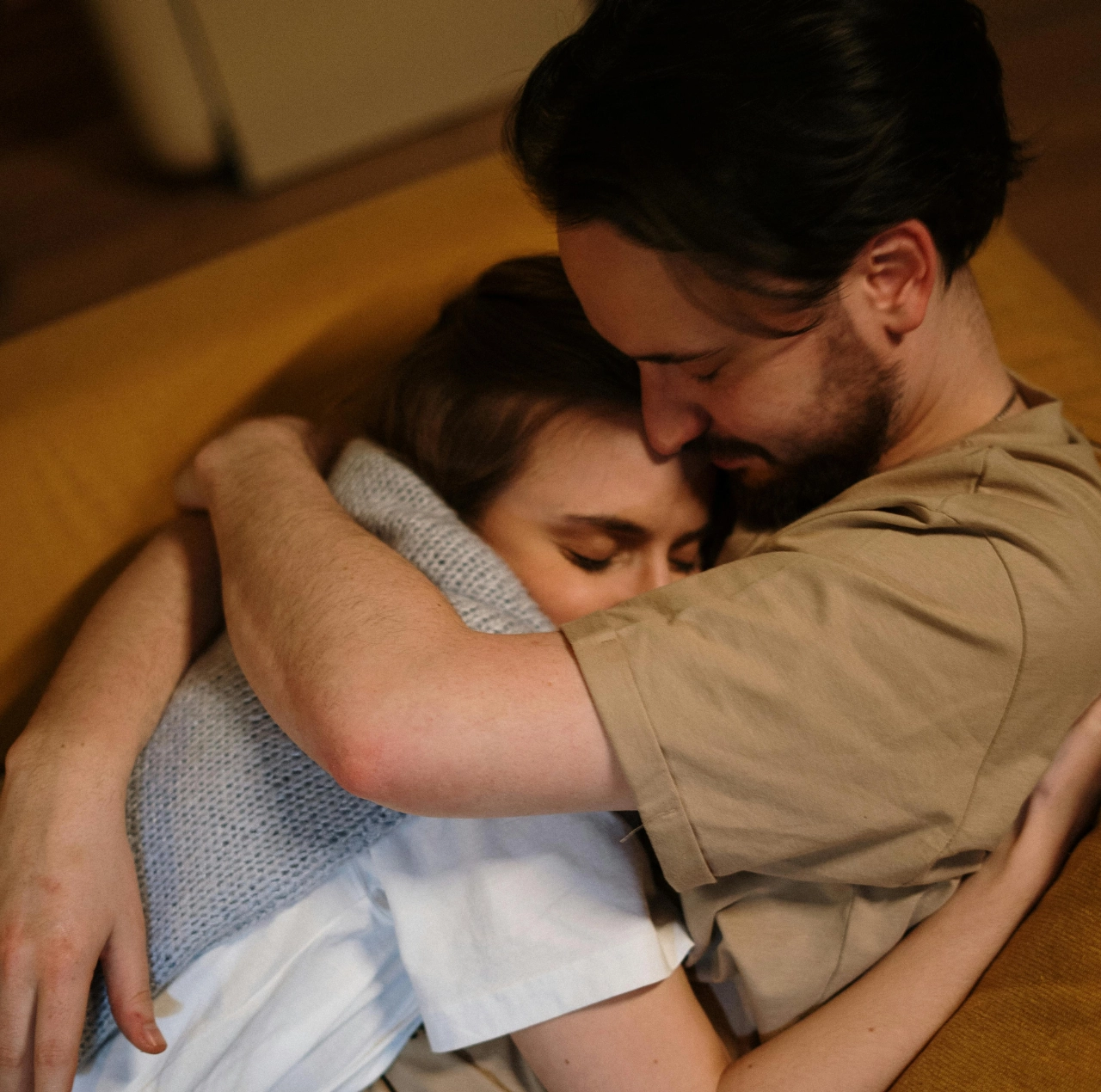 Pareja abrazándose con ternura en un sofá, ilustrando green flags en una relación.