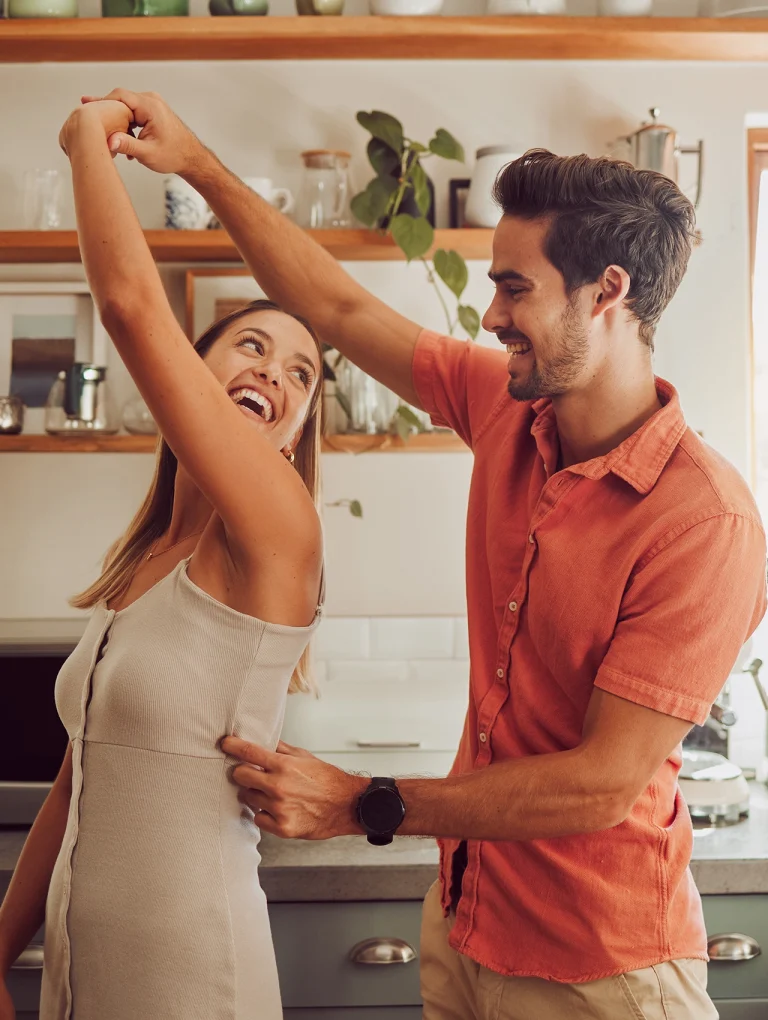 Pareja bailando con alegría en la cocina, representando green flags en una relación.