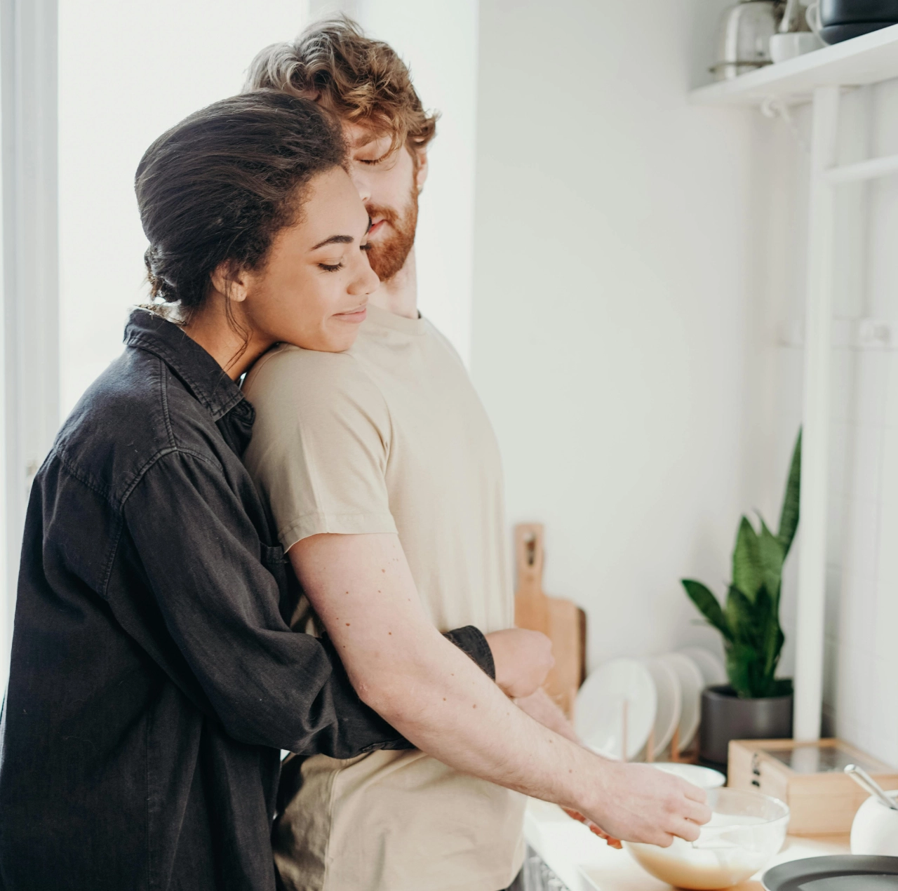 Pareja abrazándose en la cocina mientras cocinan, representando cuáles son los lenguajes del amor.