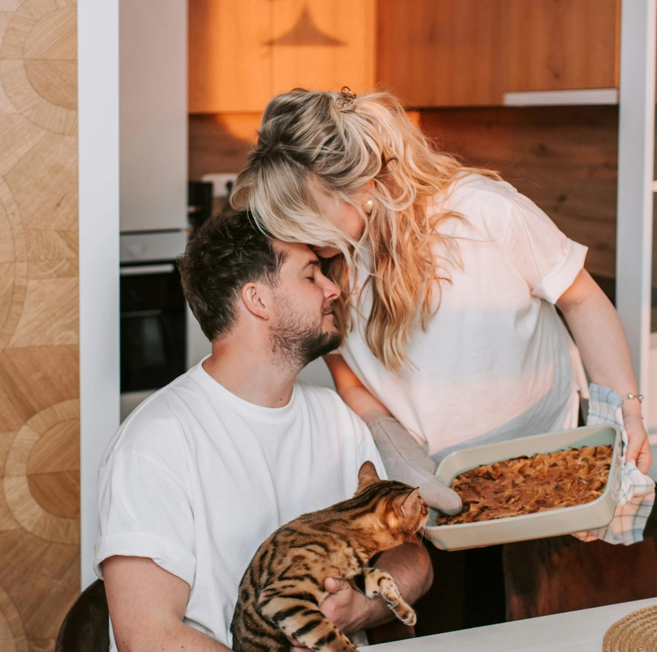Pareja mostrando afecto en casa mientras comparten una comida, ilustrando cuáles son los lenguajes del amor.