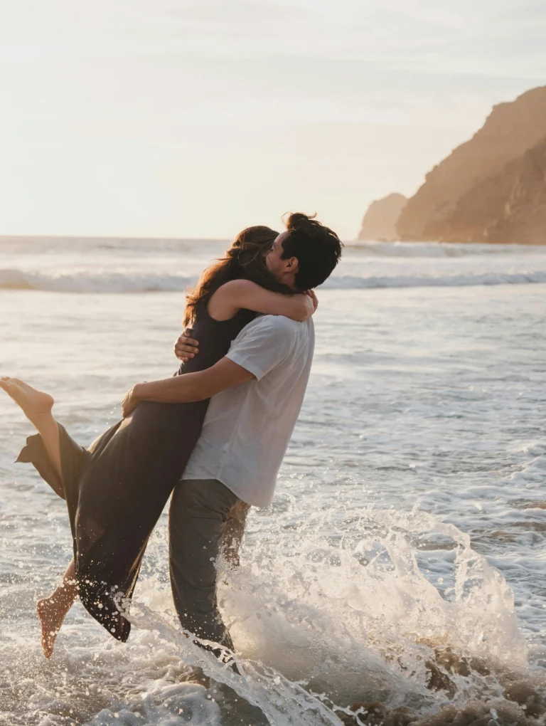 Pareja abrazándose en la playa al atardecer – cómo saber si un hombre está enamorado sin preguntarle