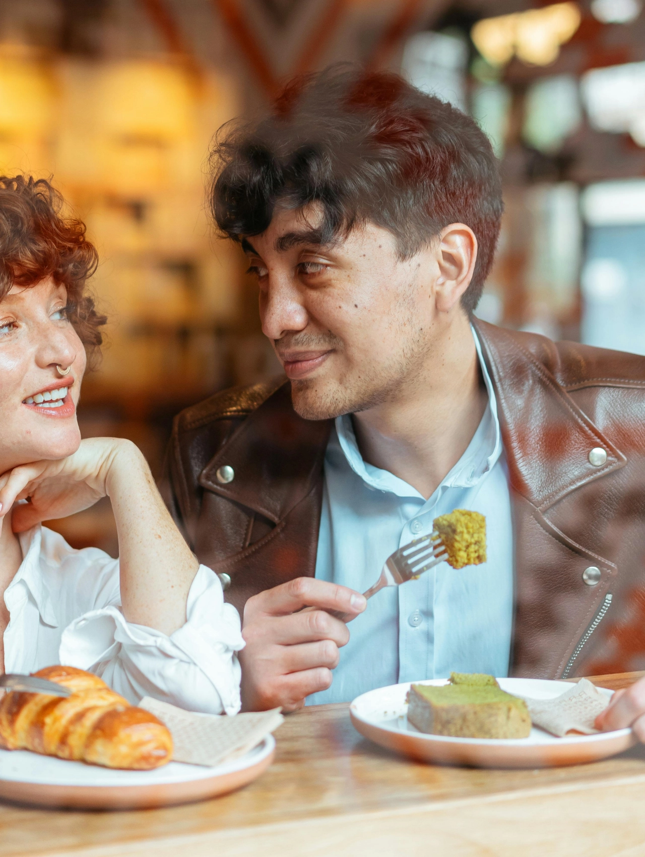 Hombre mirando con ternura a una mujer en una cafetería, representando "cómo saber si un hombre está enamorado