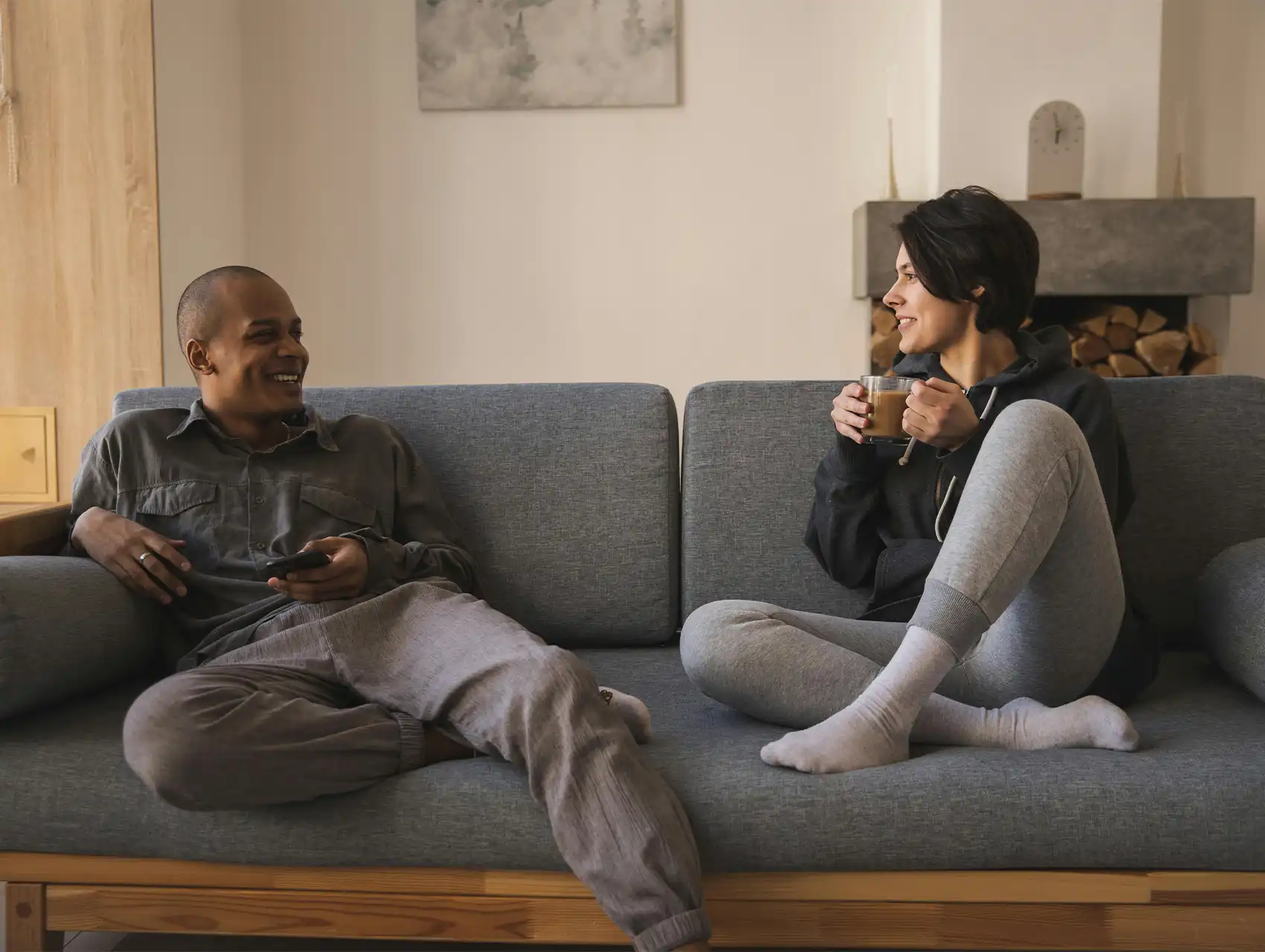 Pareja sonriendo en el sofá mientras conversan — cómo mejorar la comunicación en pareja