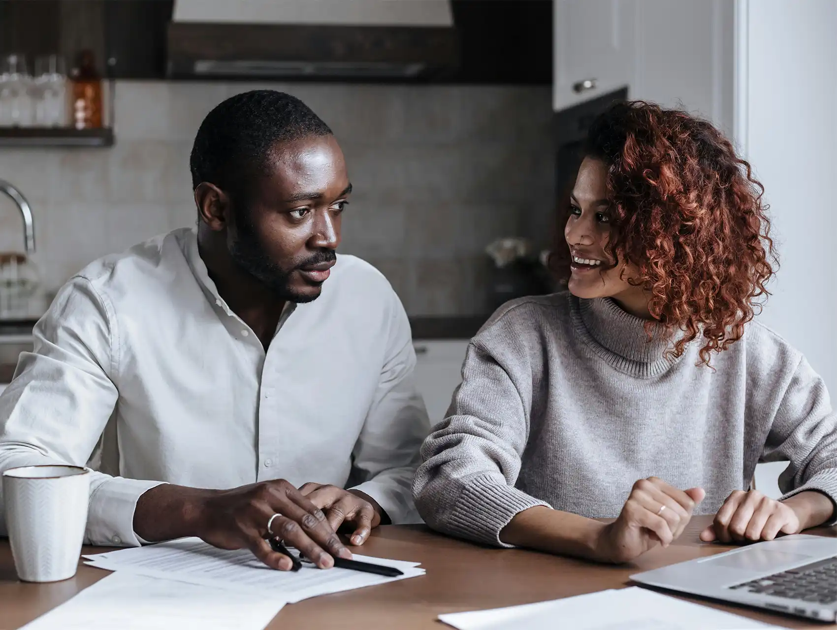 Pareja conversando en la cocina mientras revisan documentos — cómo mejorar la comunicación en pareja