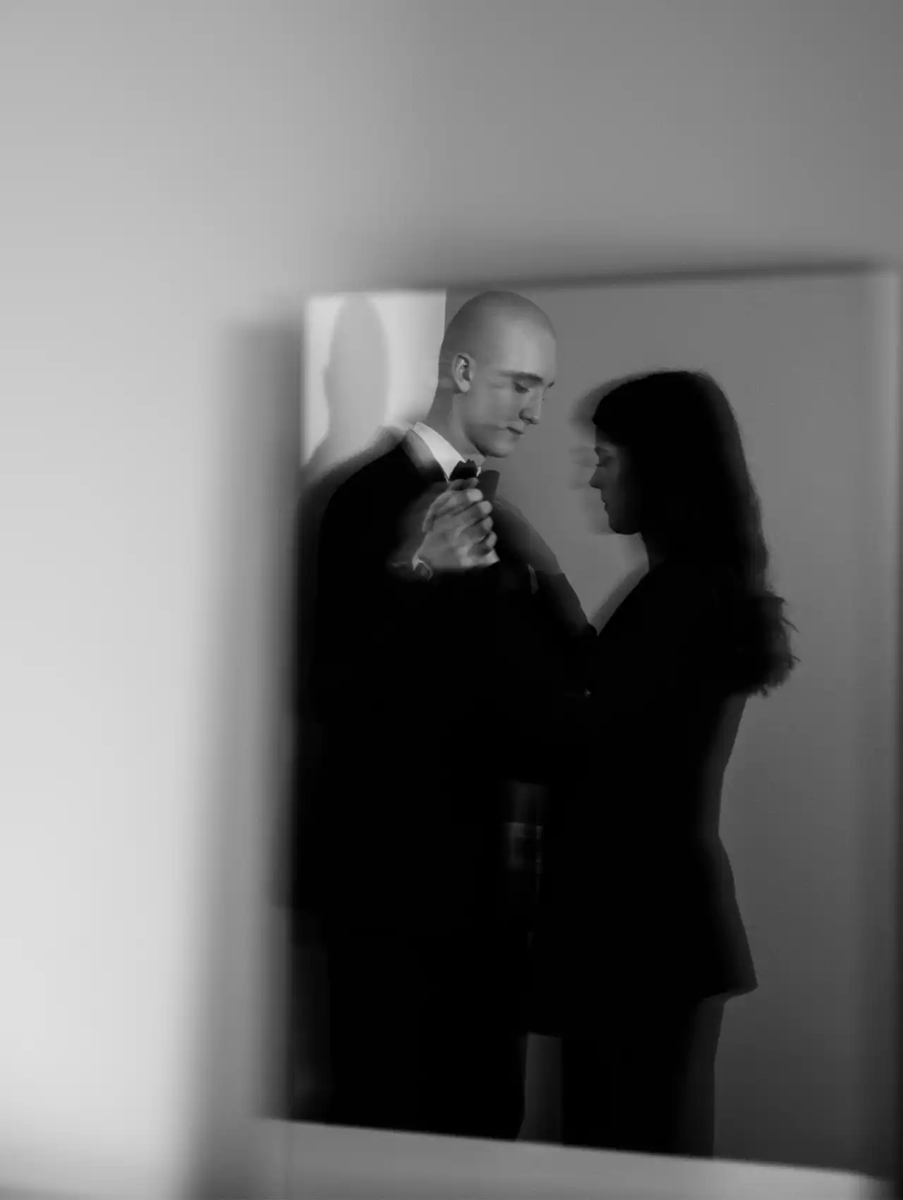 Reflejo de una pareja abrazada en un espejo en blanco y negro, explorando el apego en las relaciones de pareja.