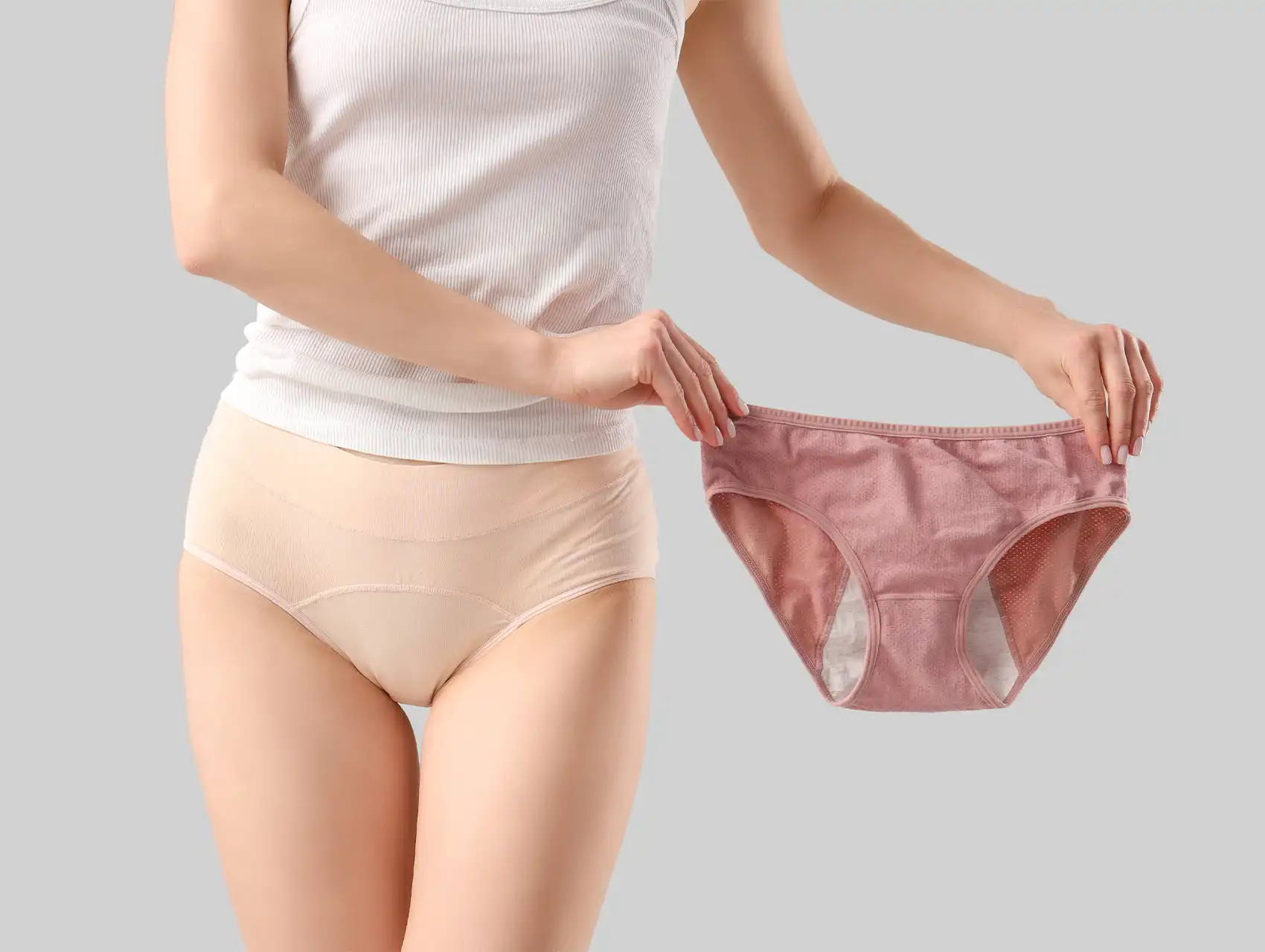 Mujer mostrando dos modelos de calzones menstruales en tonos nude y rosa