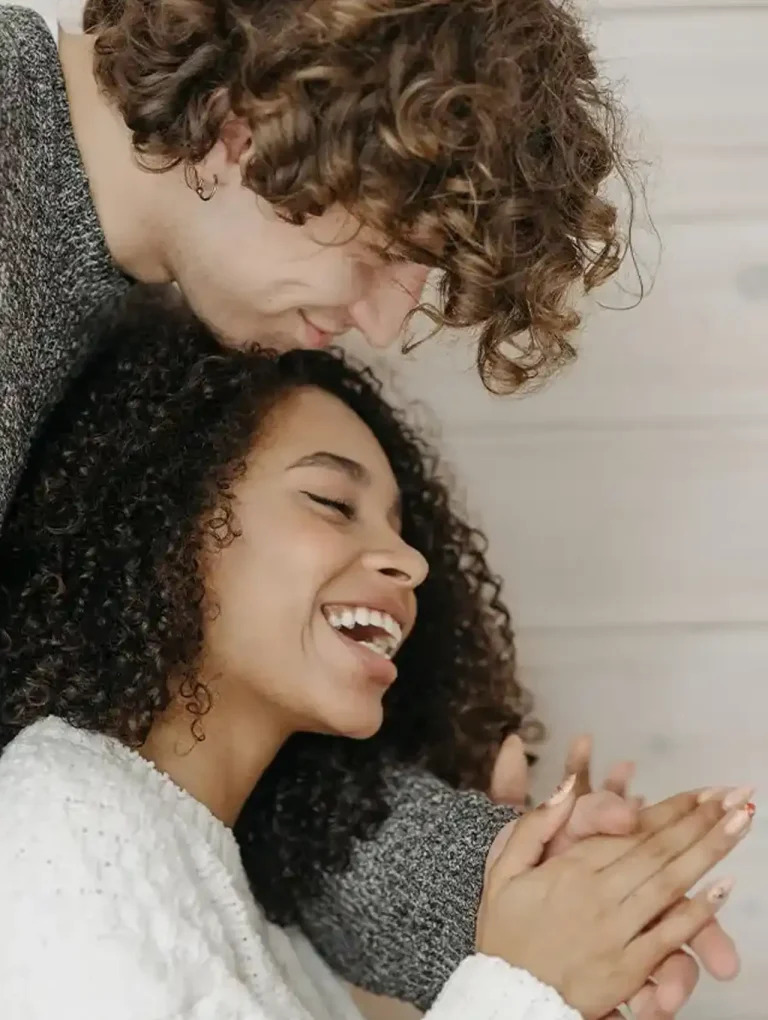 Pareja abrazada y riendo juntos en un momento íntimo – comunicación asertiva en pareja y complicidad