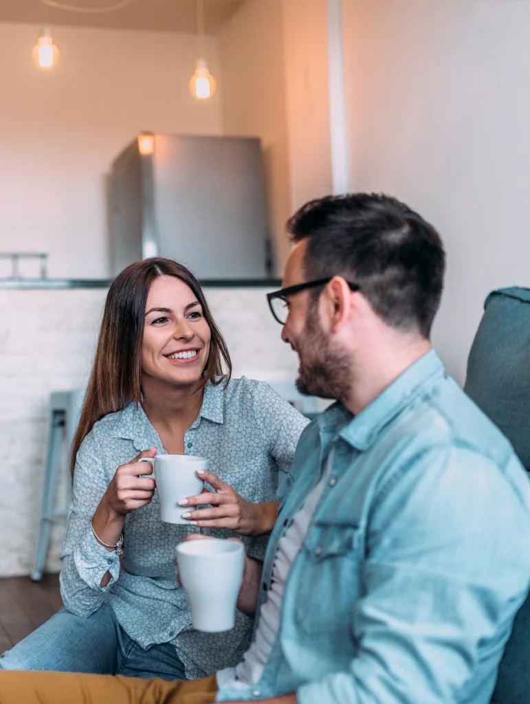 Pareja conversando y sonriendo en casa representando la importancia de la comunicación en pareja.