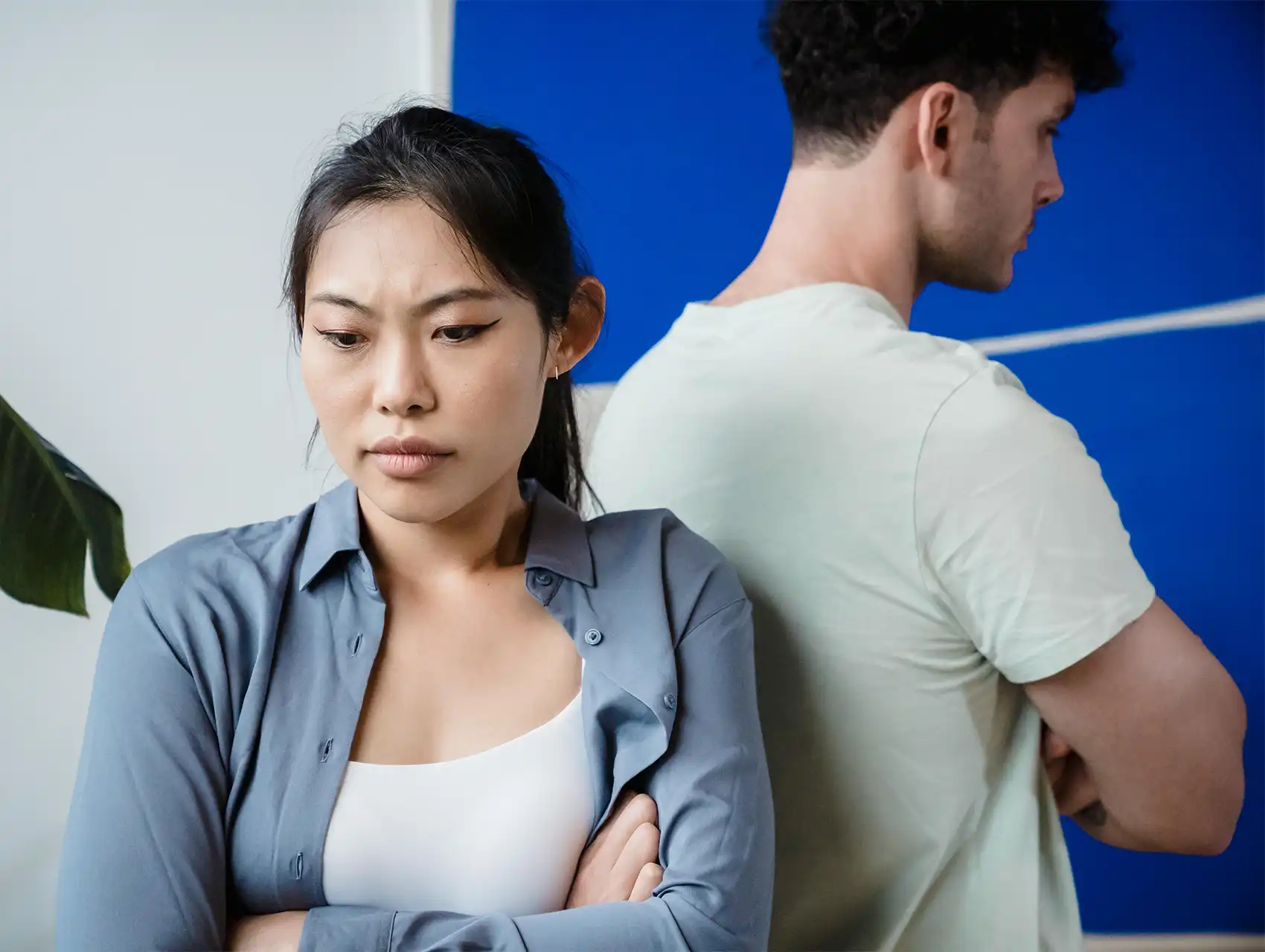 Mujer preocupada y hombre molesto de espaldas – conflictos en pareja