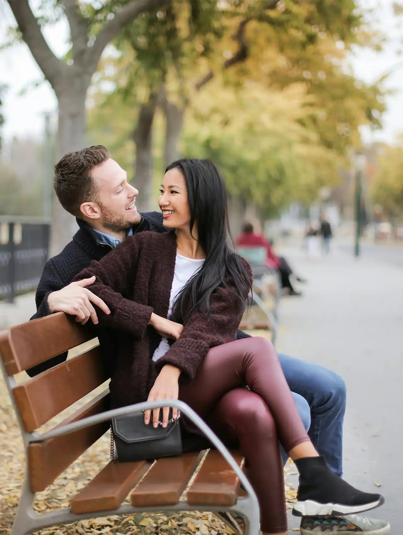 Pareja sentada en un parque otoñal sonriendo, representando ejemplos de límites sanos en una relación