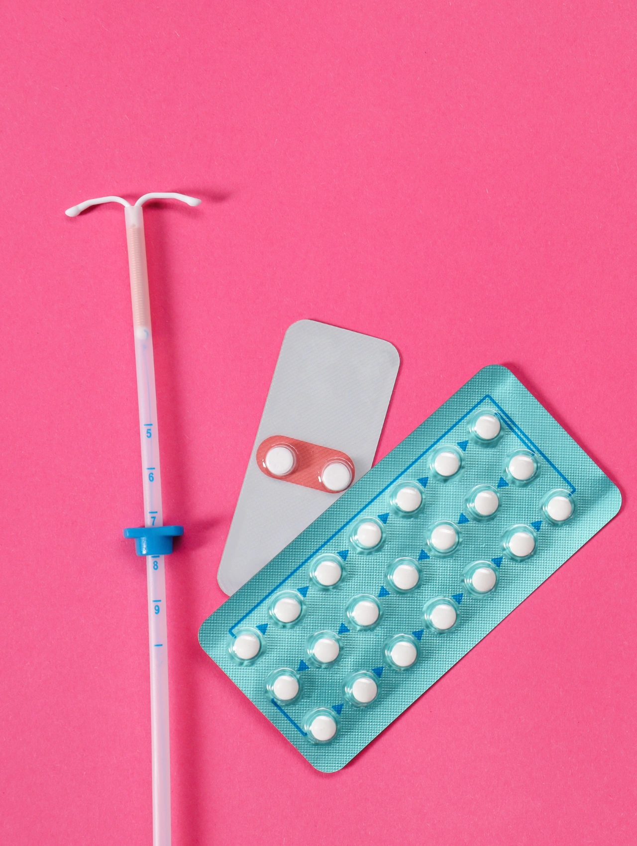 Diferentes métodos anticonceptivos sobre fondo rosa, resaltando la importancia de preguntarse si las pastillas anticonceptivas son seguras y cómo sentirse más tranquila al usarlas.