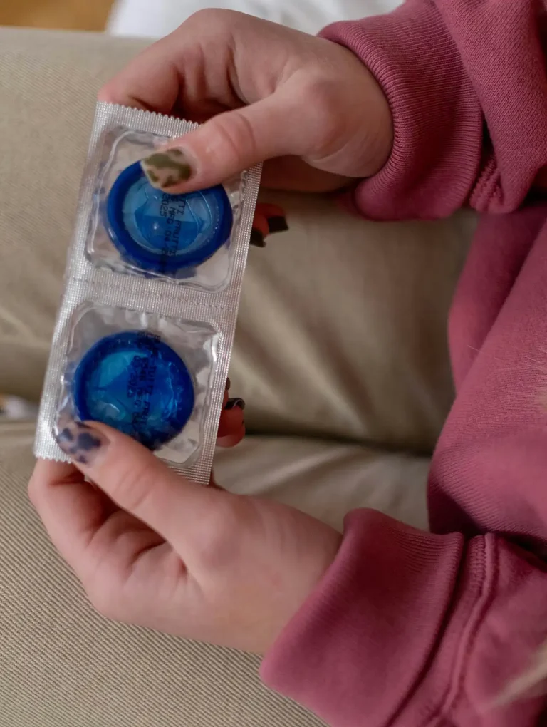 Manos de una mujer sosteniendo condones azules — preguntas sobre los métodos anticonceptivos