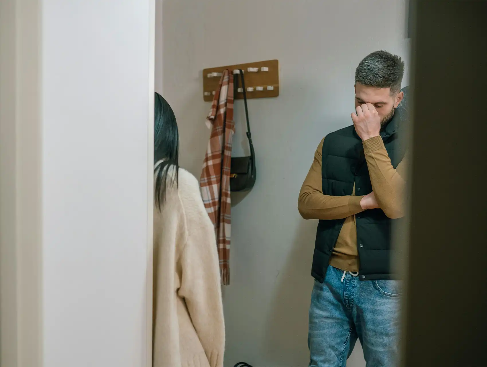 Hombre preocupado y mujer alejándose tras discusión en casa – como las peleas de pareja