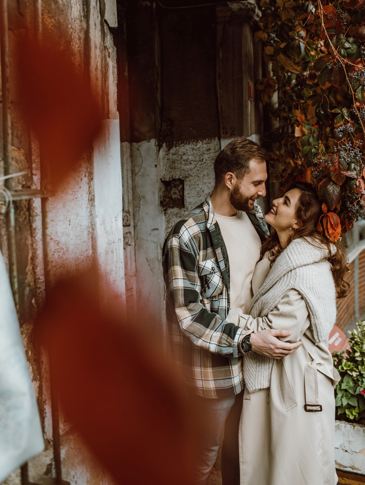Pareja abrazada en un entorno otoñal cálido, mirando el uno al otro con complicidad y transmitiendo un profundo amor romántico.