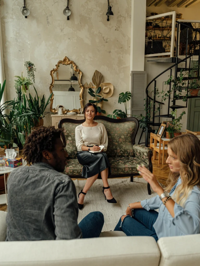 Sesión de terapia matrimonial con una pareja y terapeuta en sala acogedora, ayuda matrimonial gratis en América Latina.