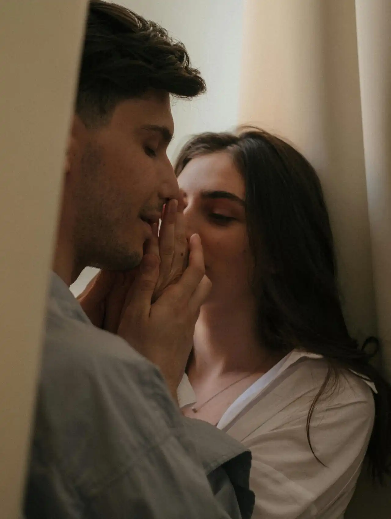 Pareja abrazándose en un momento íntimo junto a una ventana, representando como recuperar la confianza en tu pareja.