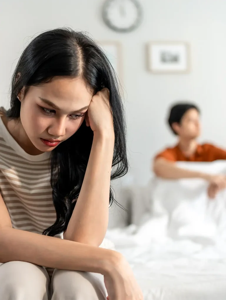 Mujer triste sentada en la cama, con la mirada baja, representando el dolor y el proceso de cómo recuperarse de una infidelidad de mi esposa.