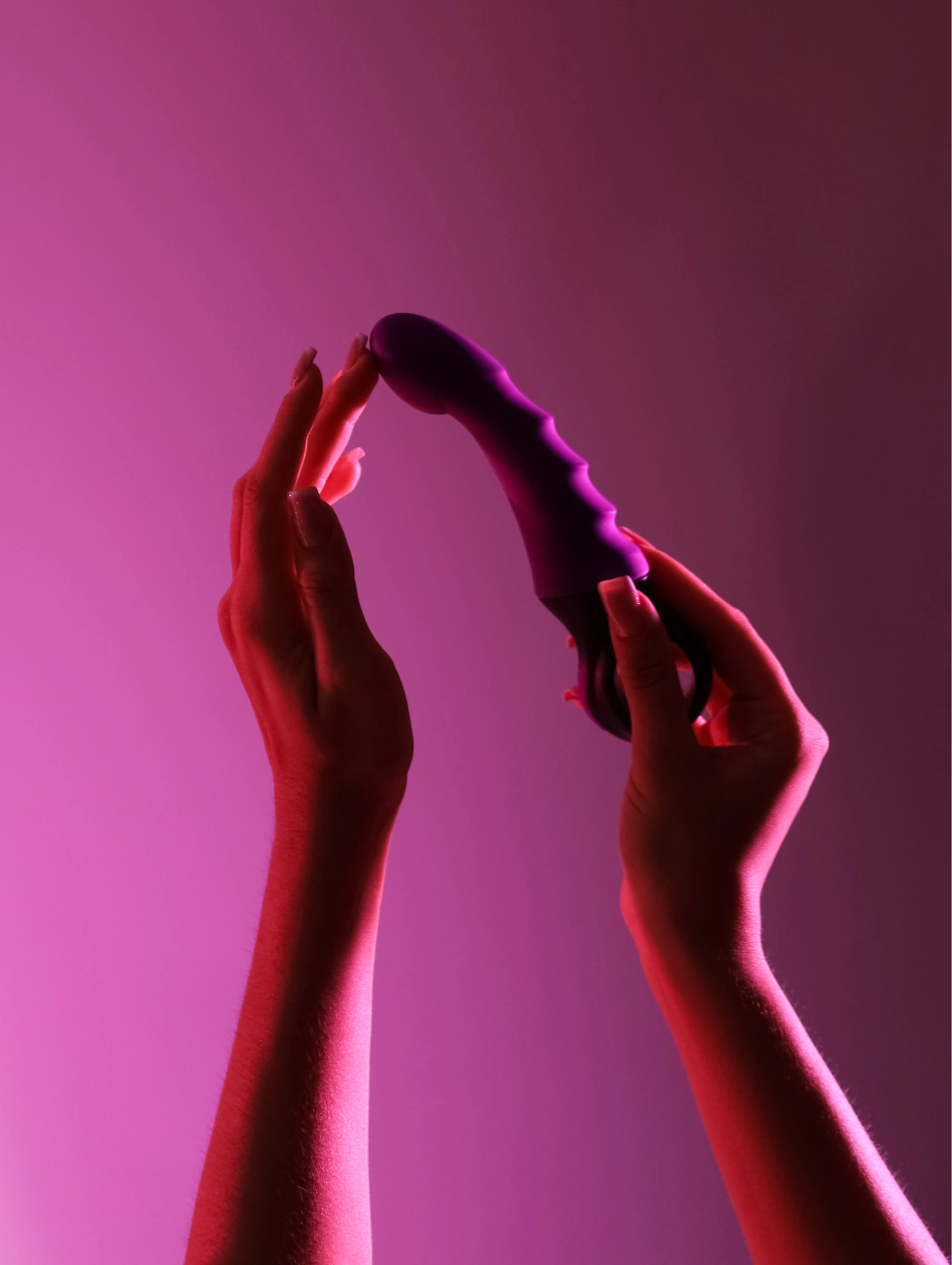 Vibrador morado de última generación sostenido con las manos, uno de los juguetes sexuales para mujeres más vendidos.