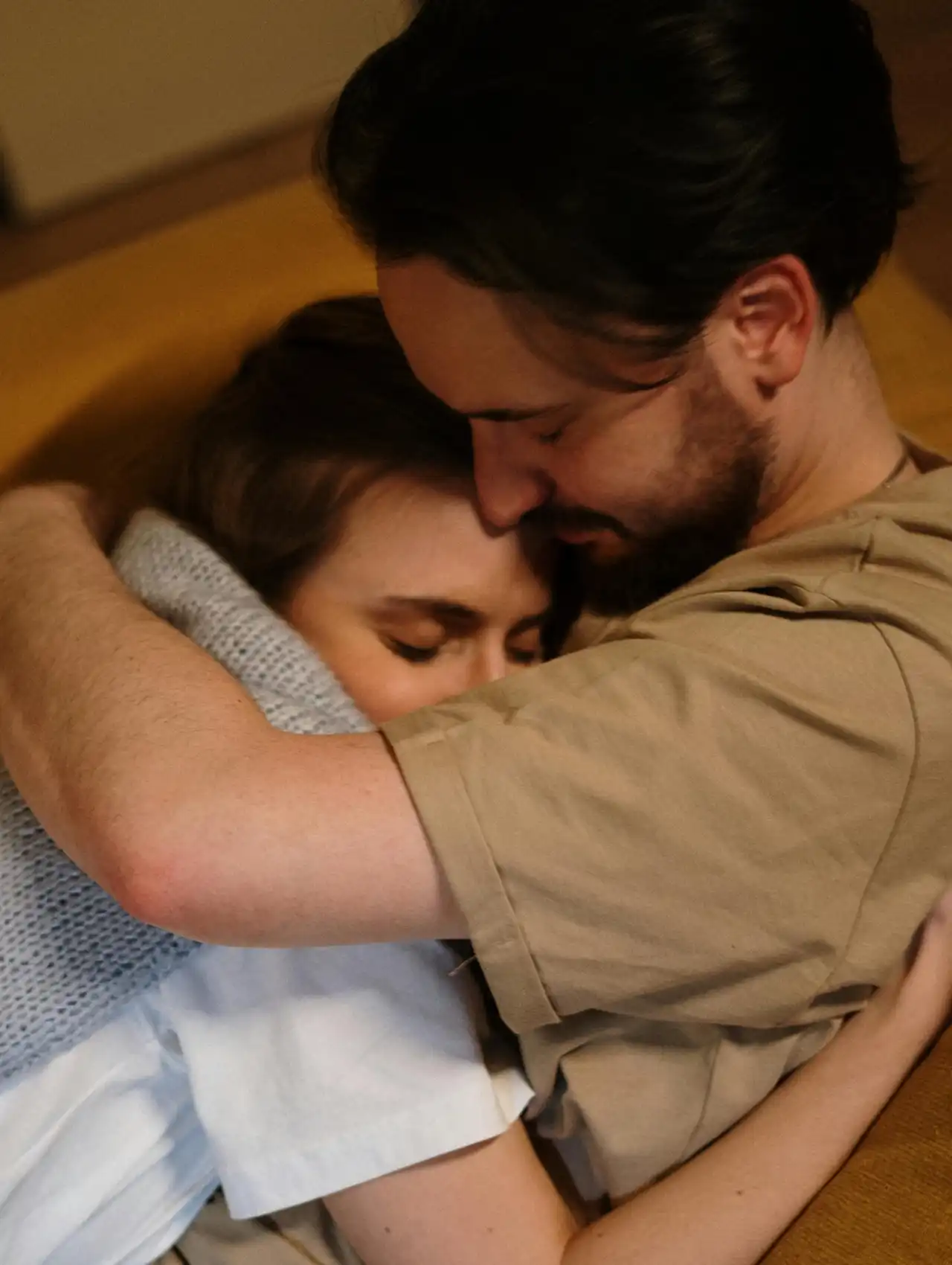 Pareja abrazándose con ternura en casa, mostrando confianza y cariño como green flags en una relación.