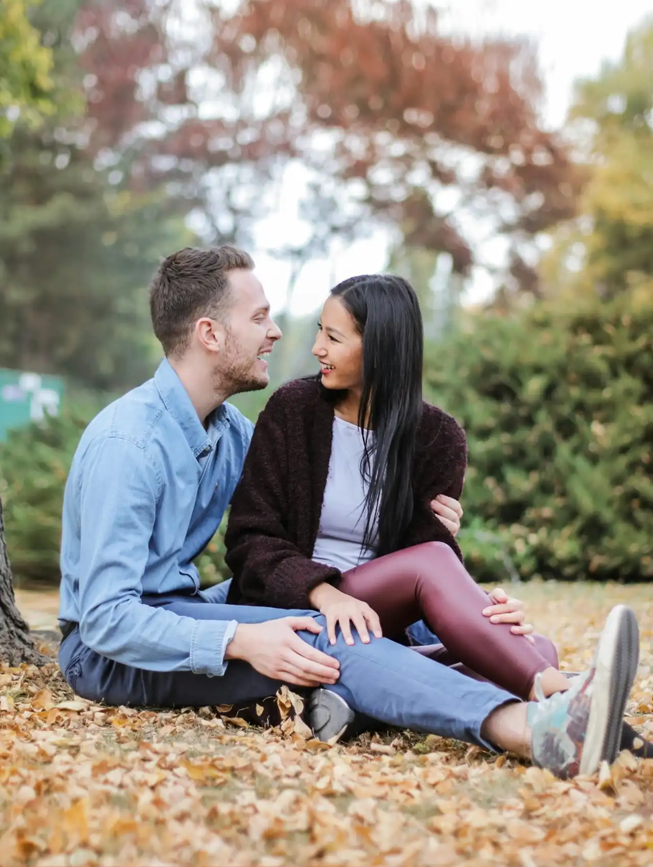 Pareja sonriendo y conversando al aire libre en un parque durante el otoño, ejemplo de green flags en una relación.