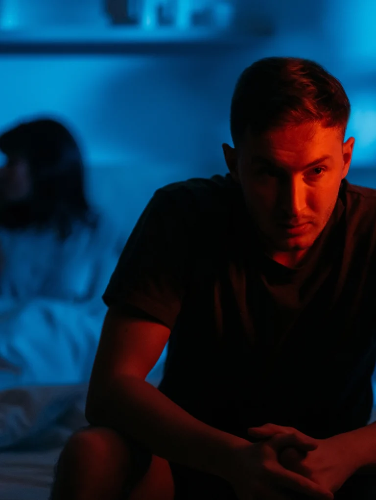 Hombre pensativo en una habitación oscura representando hombres inseguros en el amor.