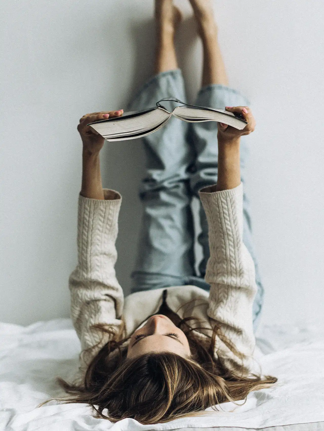 Joven acostada leyendo un libro, ideal para ilustrar momentos de lectura de libros de romance juvenil.