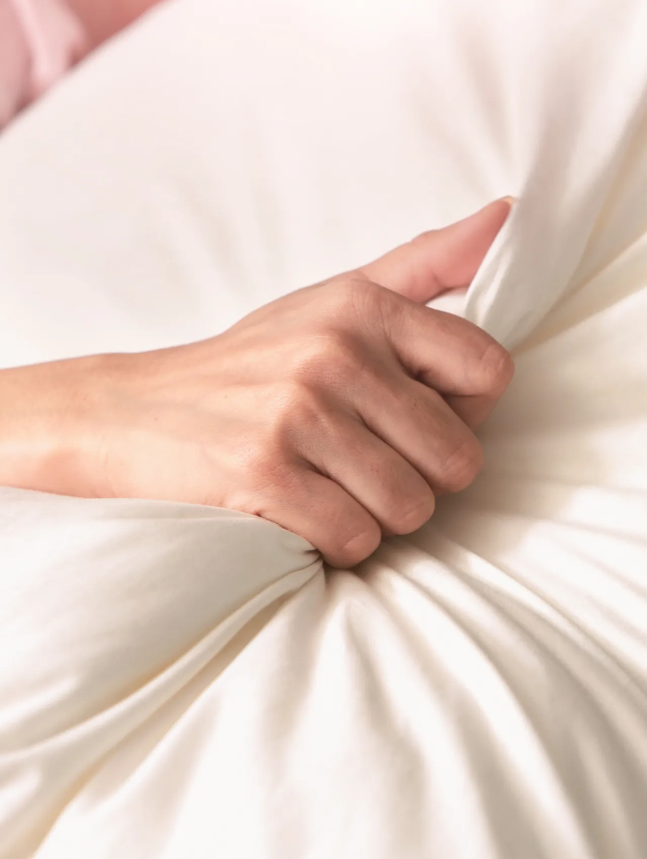 Mano apretando las sábanas, símbolo de placer intenso relacionado con el orgasmo de pezón.
