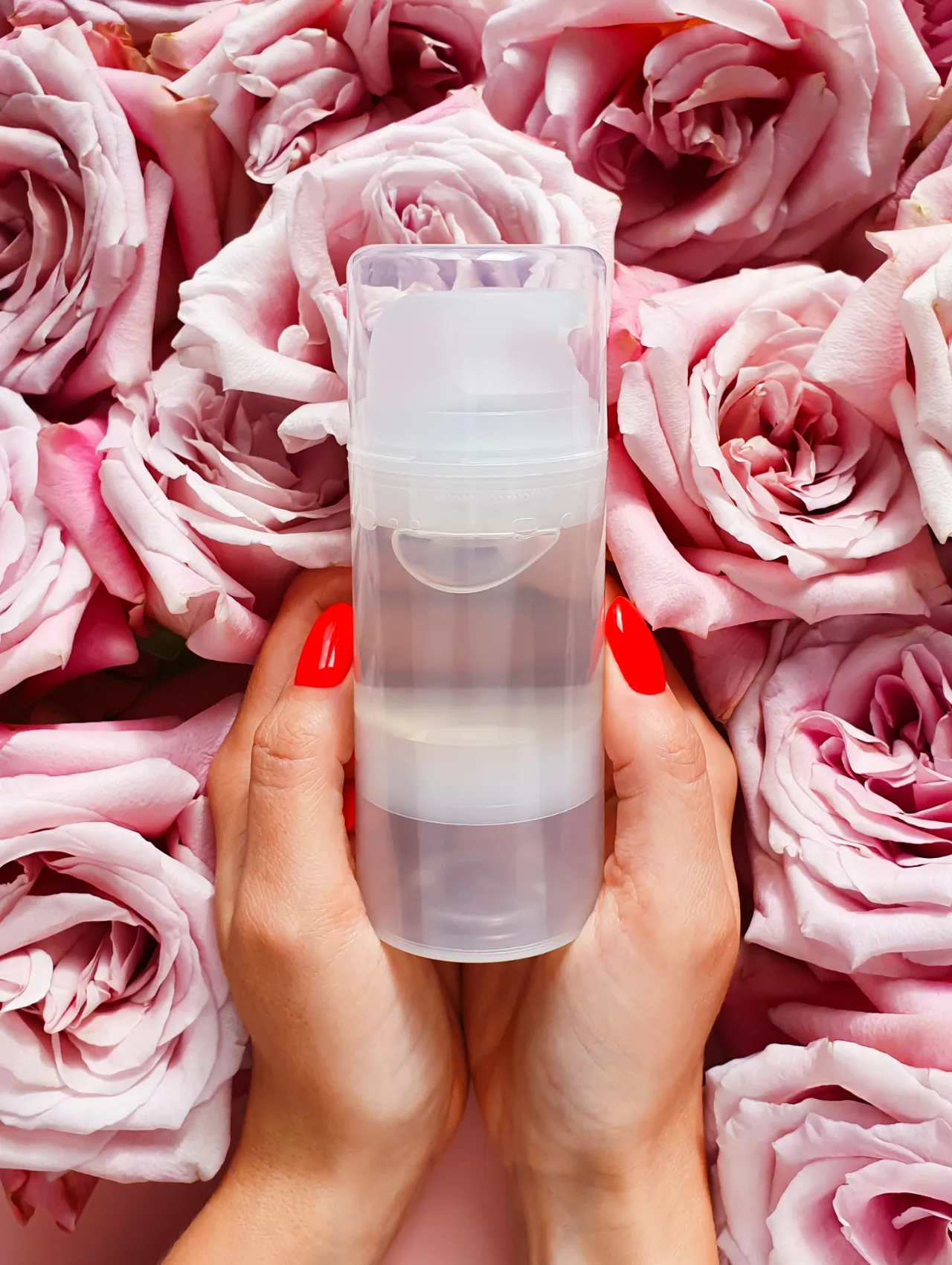 Manos femeninas con uñas rojas sosteniendo un lubricante, sugerido para intensificar el orgasmo de pezón.