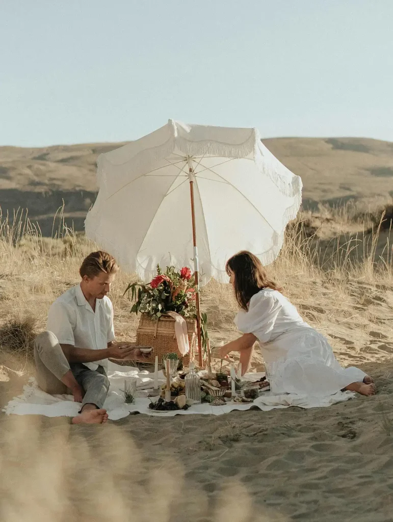 Pareja disfrutando de un picnic bohemio en las dunas durante una cita especial, citas románticas