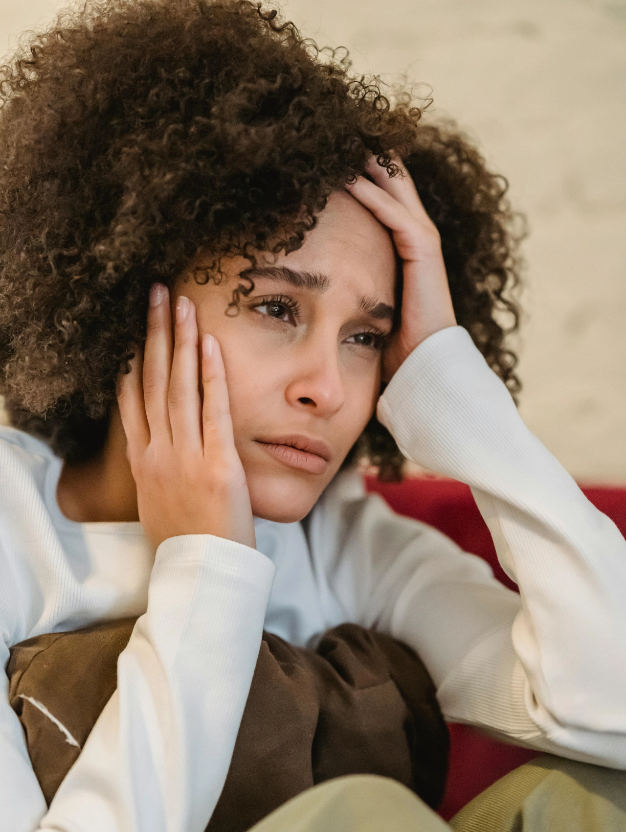 Mujer con expresión de tristeza sosteniendo su cabeza, representando el dolor emocional tras una ruptura, cómo superar una ruptura amorosa.