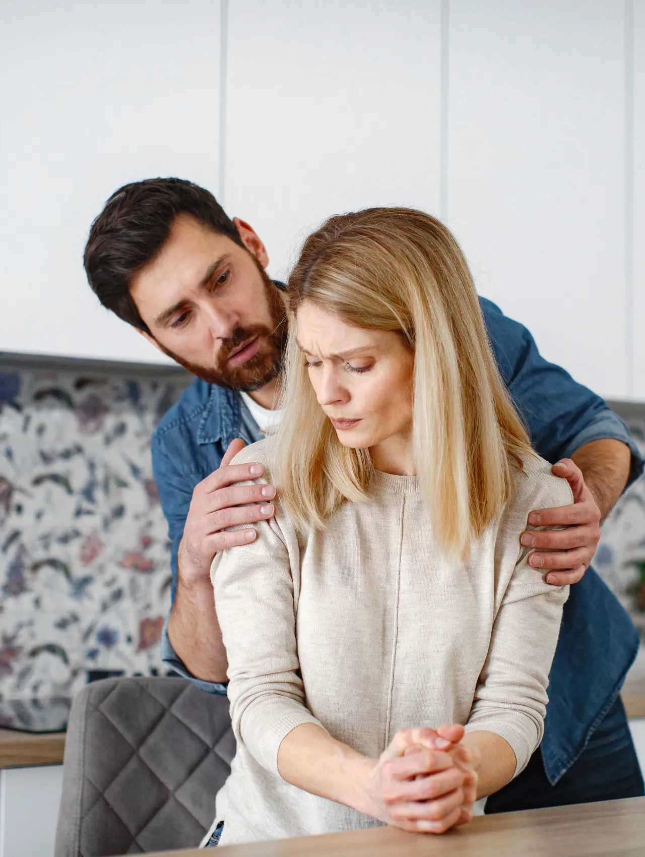 Mujer con gesto de tristeza y pareja intentando consolarla, reflejando red flags en una relación.