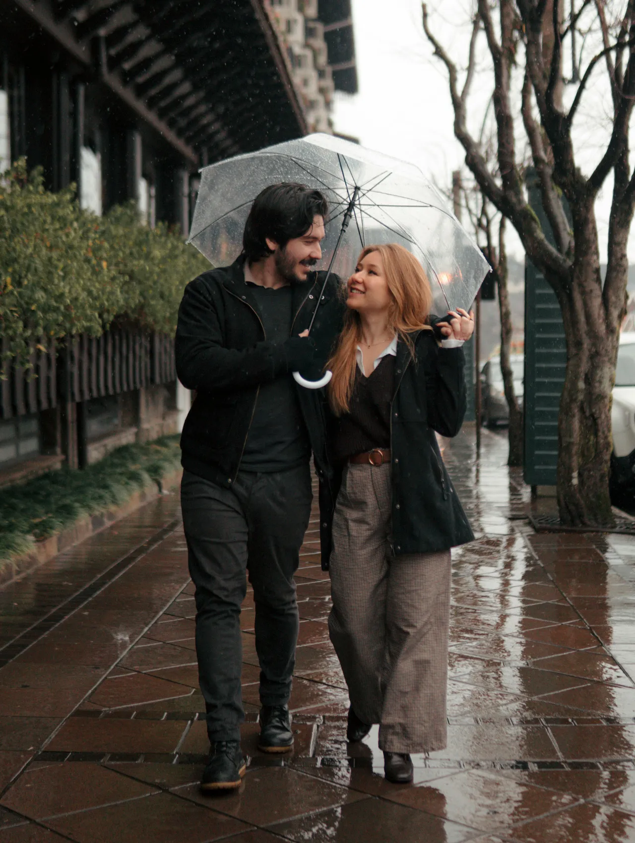 Pareja caminando bajo la lluvia con paraguas, mostrando cuidado mutuo y señales de una relación seria.