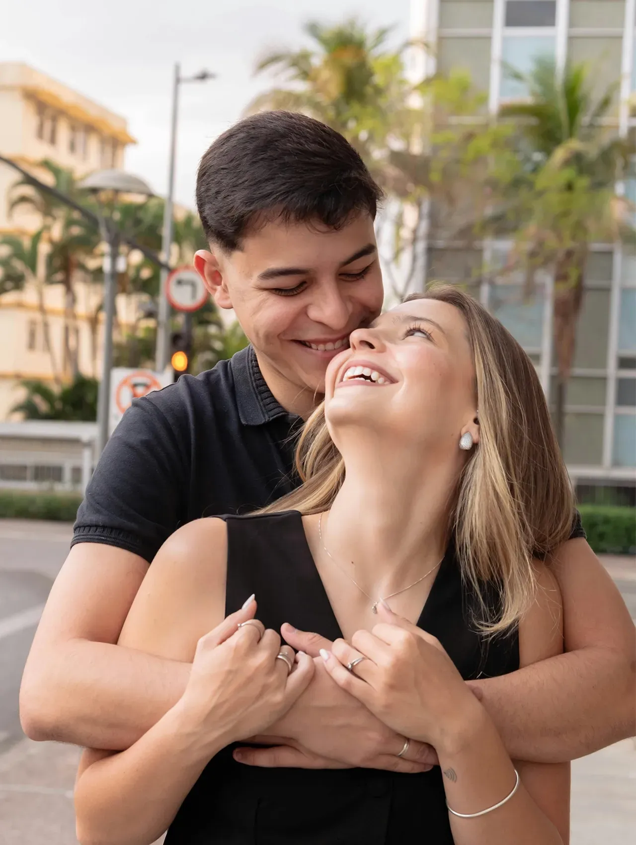 Pareja abrazándose y sonriendo en la calle, mostrando complicidad y señales de una relación seria.
