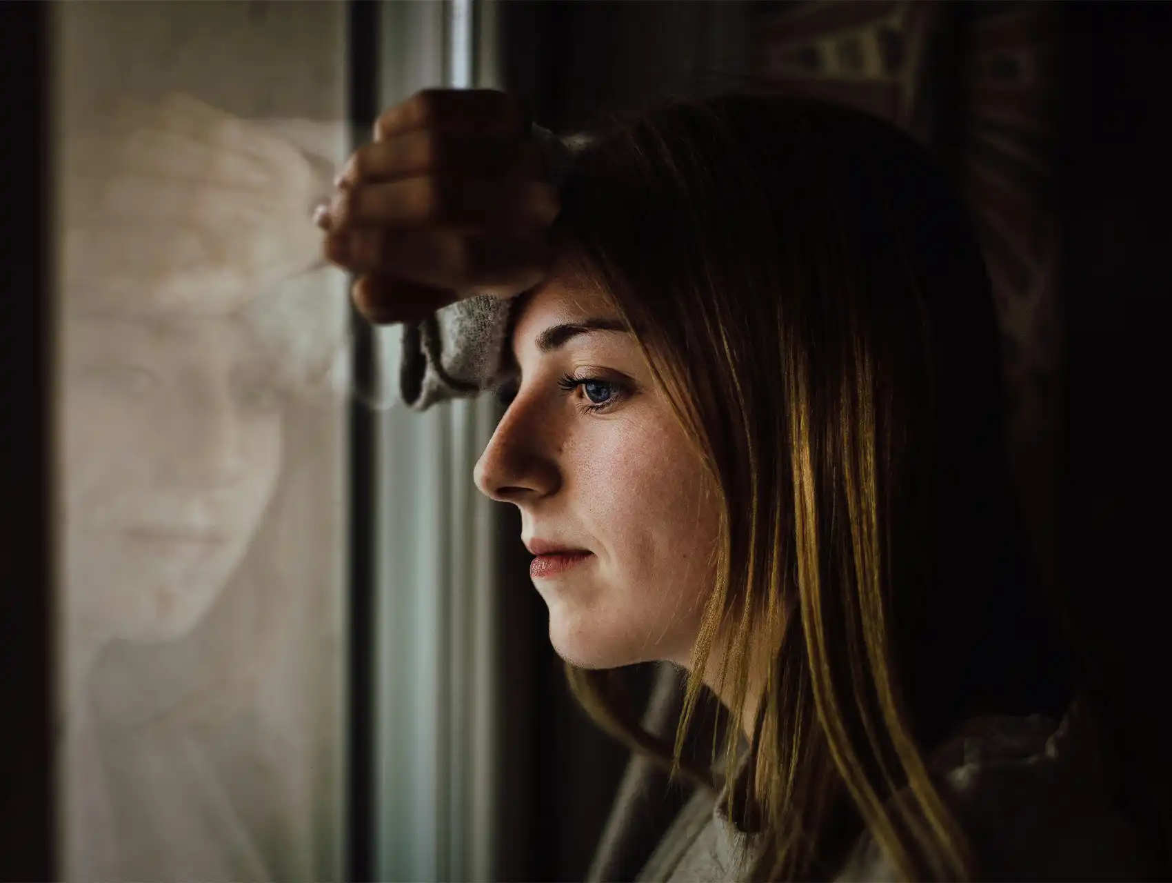 Mujer pensativa mirando por la ventana, ejemplo de señales de infidelidad de una mujer.