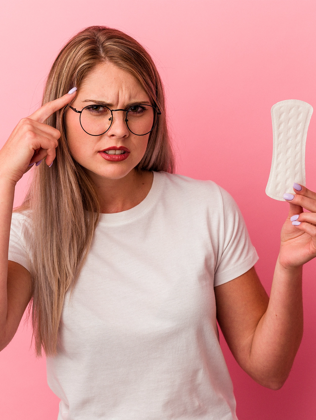 Mujer confundida sosteniendo un protector diario y señalando su cabeza, imagen para artículo sobre higiene íntima y errores comunes que pueden afectar la salud.