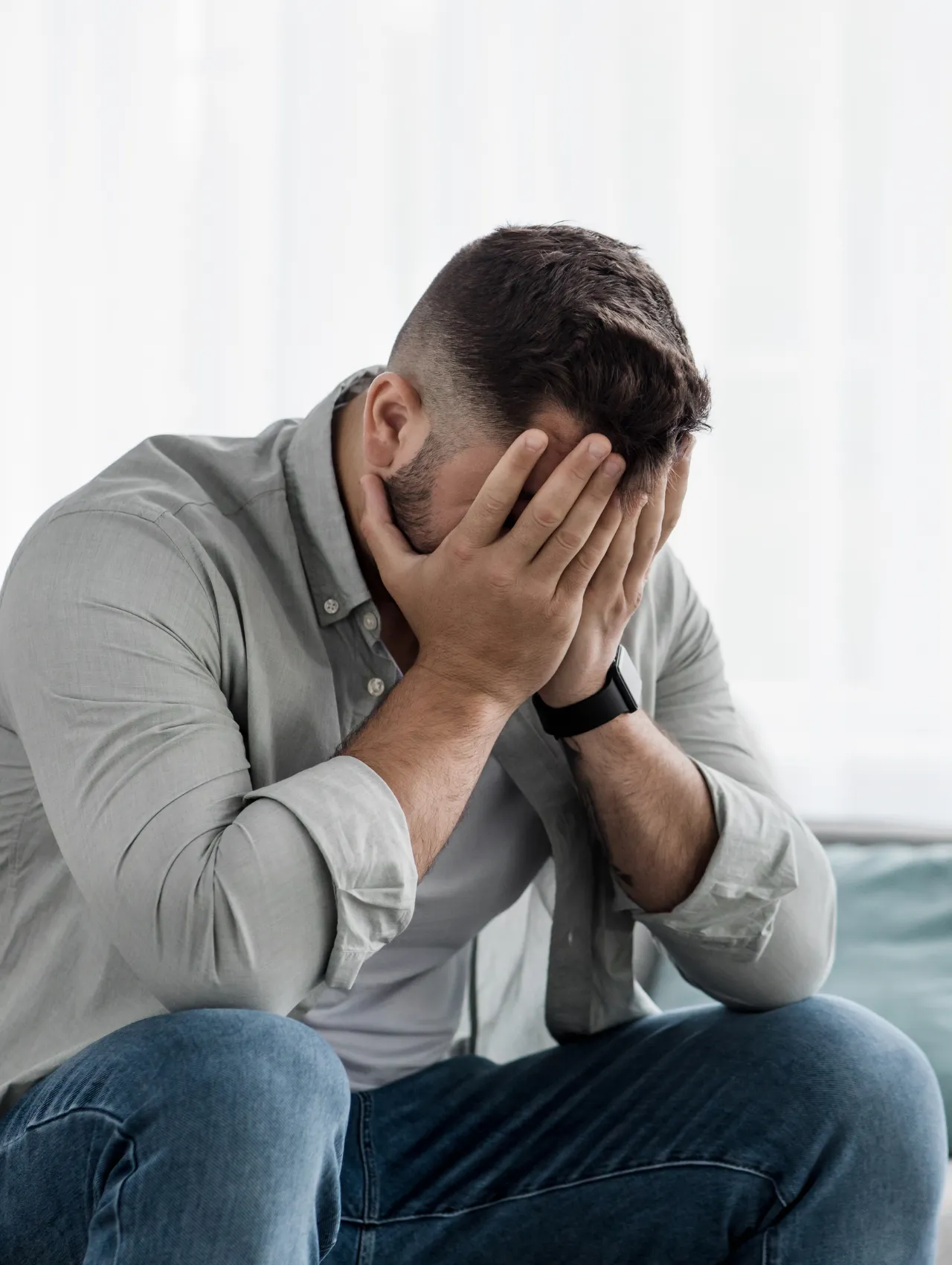 Hombre en momento introspectivo, manos en el rostro, representando factores internos detrás de la pregunta por qué un hombre pierde el deseo por su pareja, imagen conceptual de estrés, pensamientos y desconexión temporal en relaciones.