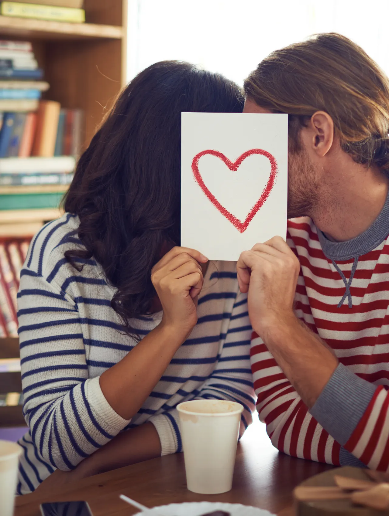 Pareja sosteniendo una tarjeta con un corazón rojo, ilustrando la importancia de las palabras de afirmación para expresar amor y reconocimiento.