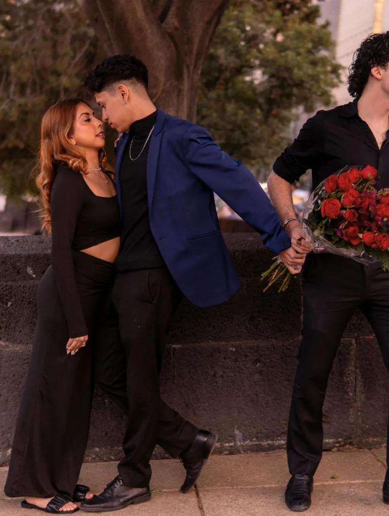 Mujer acercándose al rostro de otro hombre mientras su novio espera de espaldas con un ramo de rosas, señales de infidelidad de una mujer