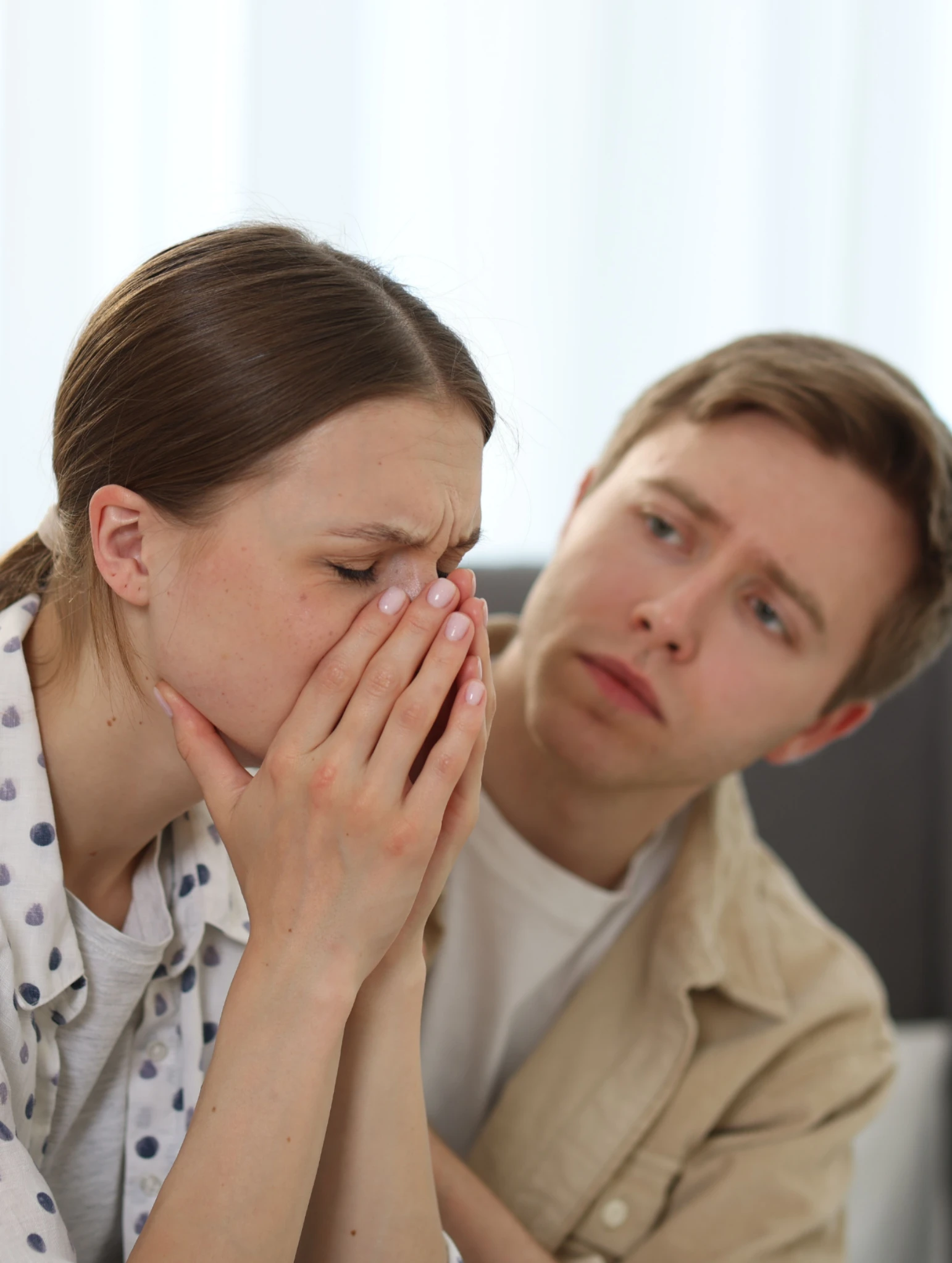 Mujer visiblemente afectada emocionalmente mientras un hombre inseguro en el amor intenta consolarla después de disculparse sin cambiar su comportamiento.