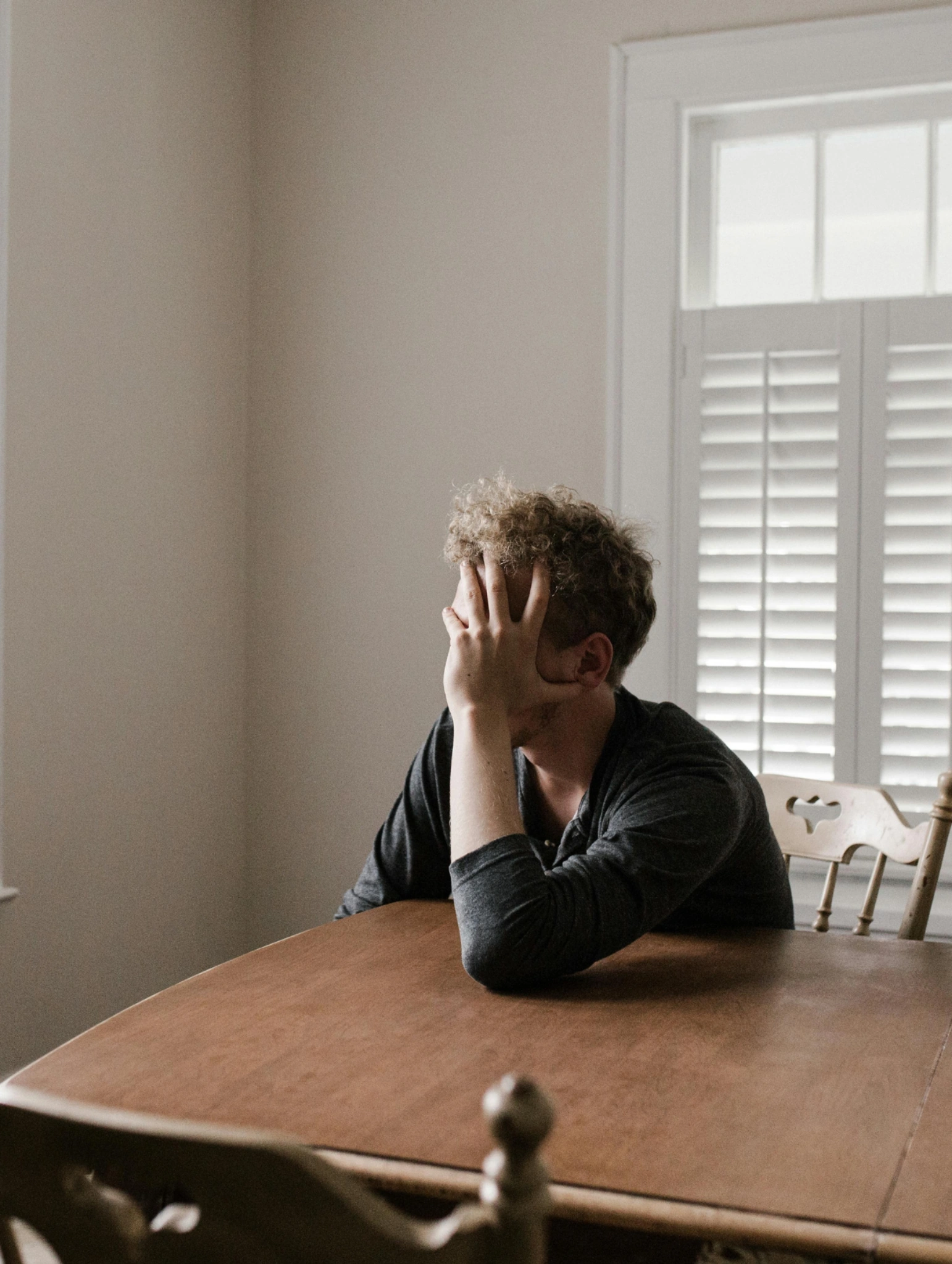 Hombre sentado solo en una mesa con la mano en el rostro, reflejando el miedo a estar solo y la carga emocional silenciosa masculina.