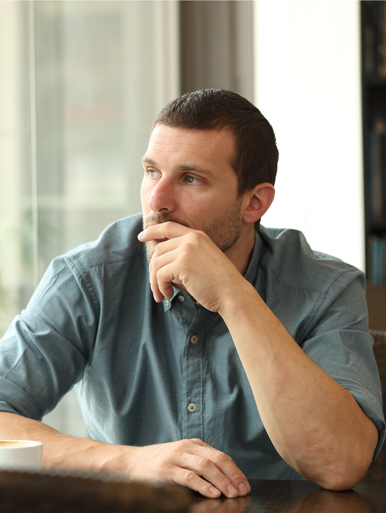 Hombre solo y pensativo junto a una ventana, representando el miedo a estar solo y la reflexión emocional masculina.