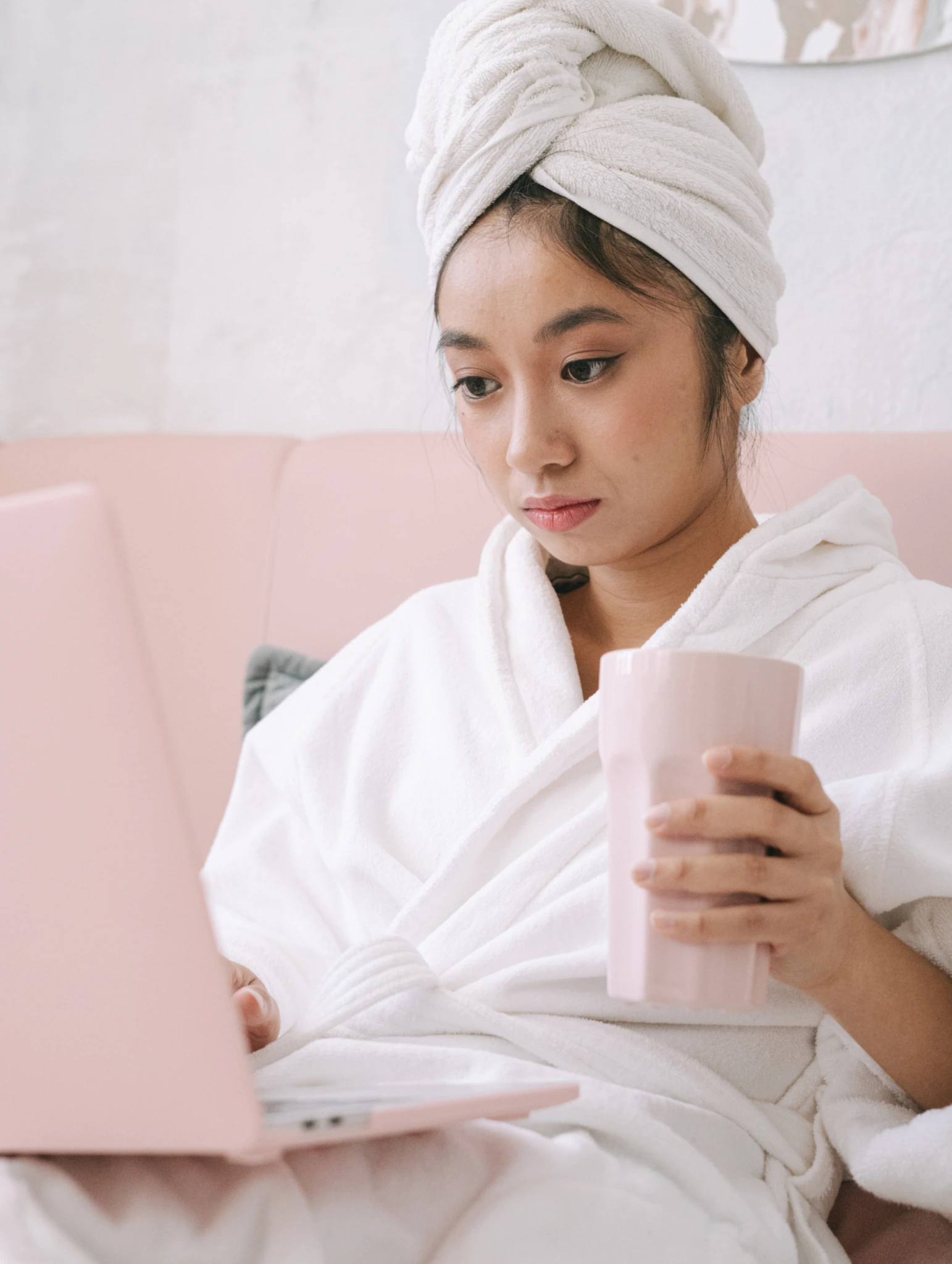 Mujer en bata con laptop y bebida, reflexionando sobre hábitos de cuidado íntimo femenino y cómo proteger el equilibrio natural.