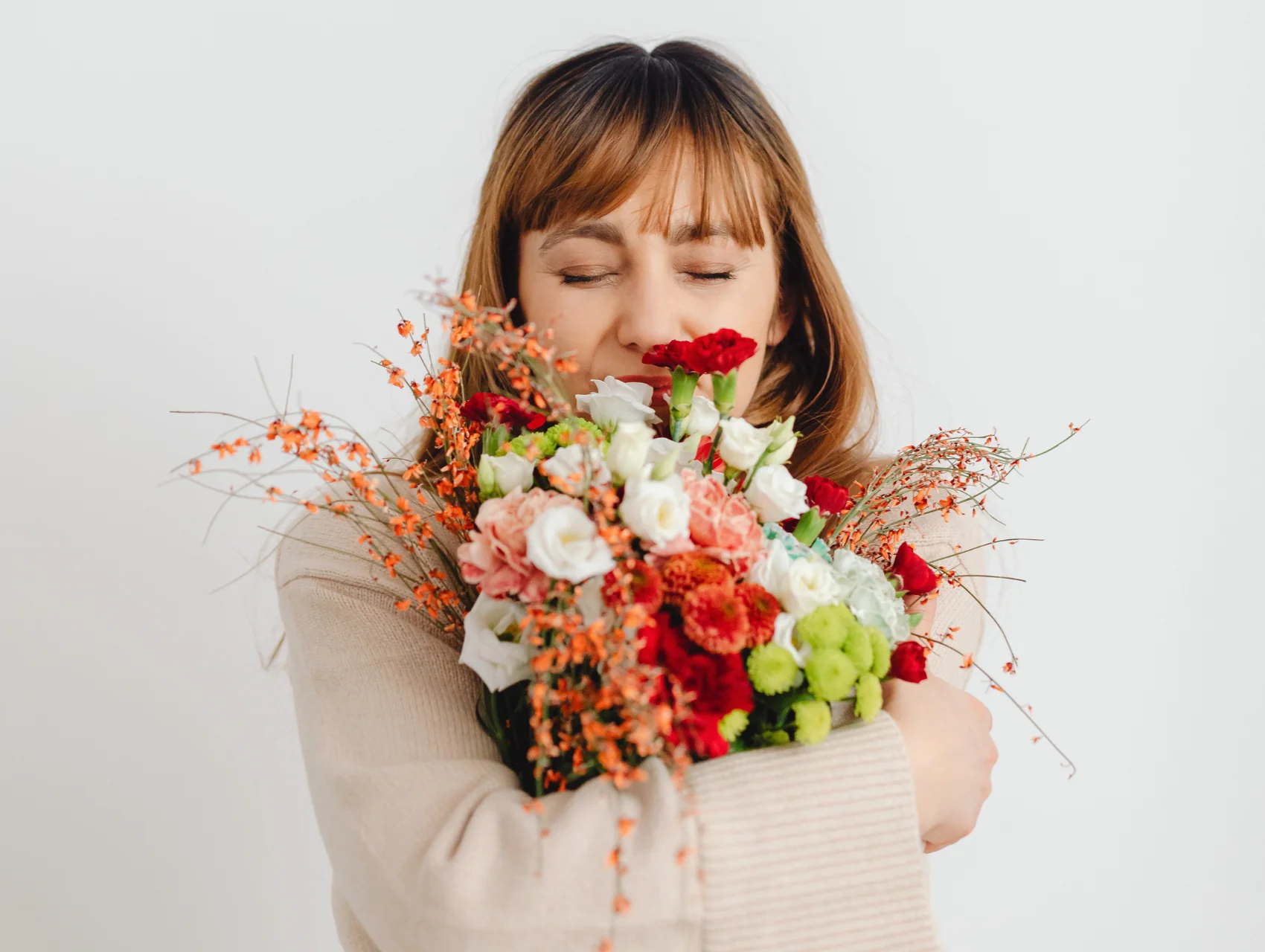 Mujer abrazando un ramo de flores con los ojos cerrados, la seguridad emocional como base de la satisfacción femenina