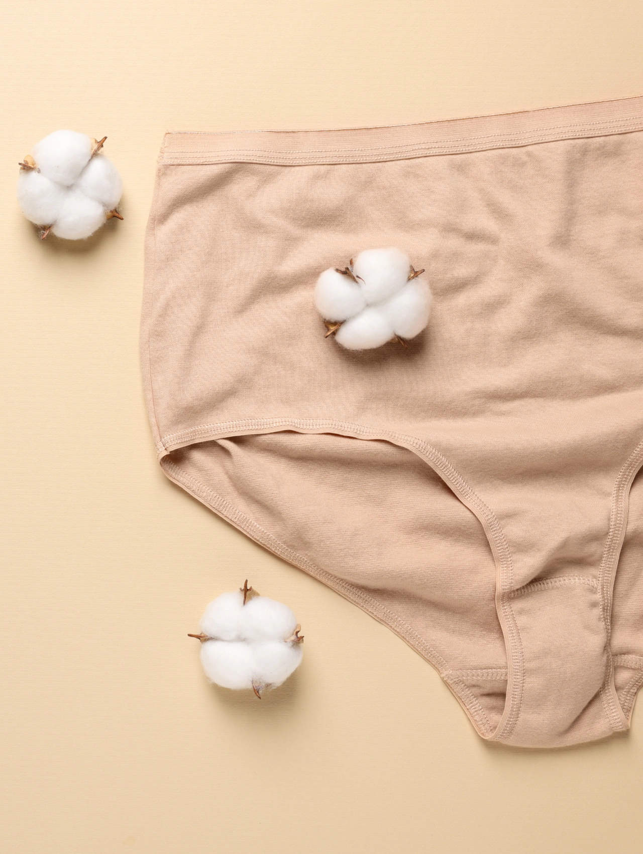 ¿Por qué aparecen granitos en la zona íntima, flat lay de ropa interior de algodón beige con flores de algodón sobre un fondo neutro suave, es normal tener granitos en la parte intima
