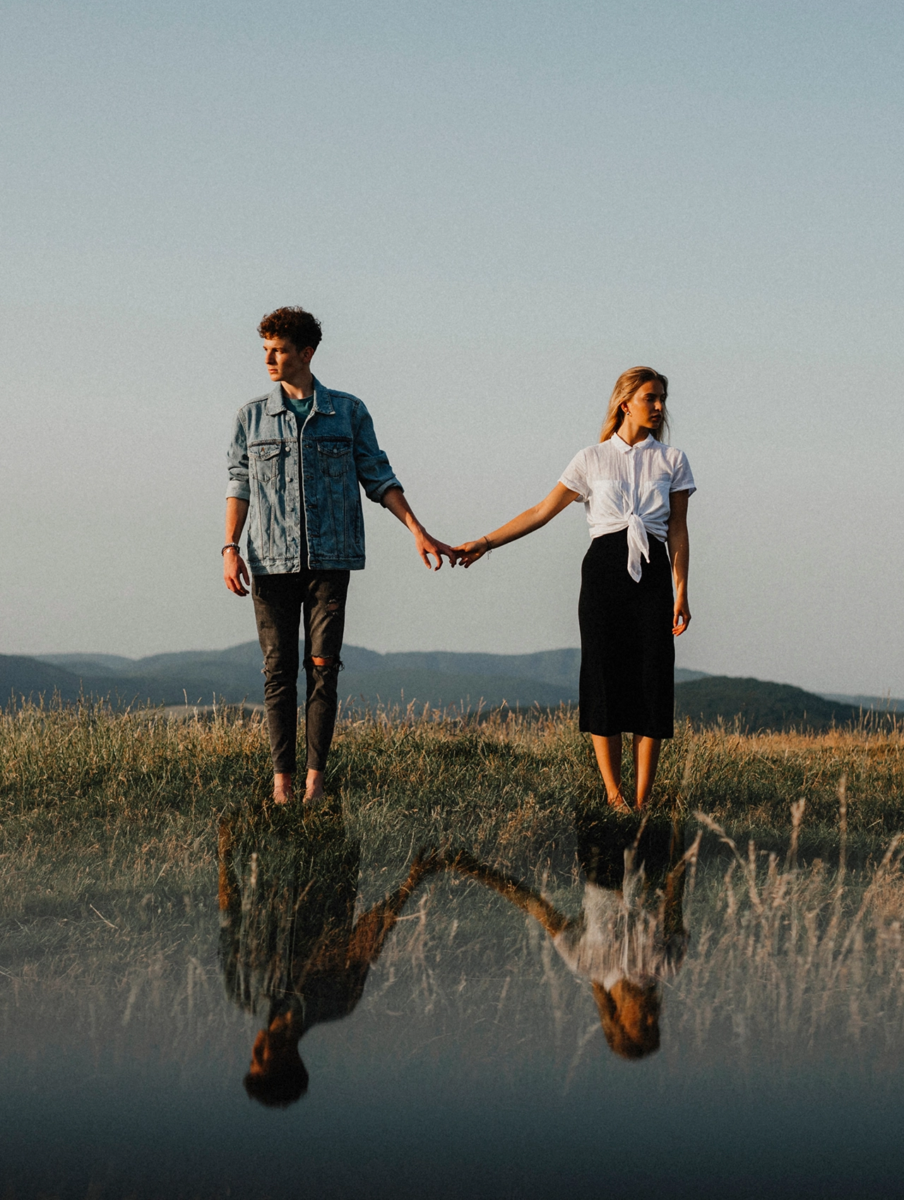 Miedo al compromiso en pareja reflejado en una relación distante con dos personas tomados de la mano pero mirando en direcciones opuestas.