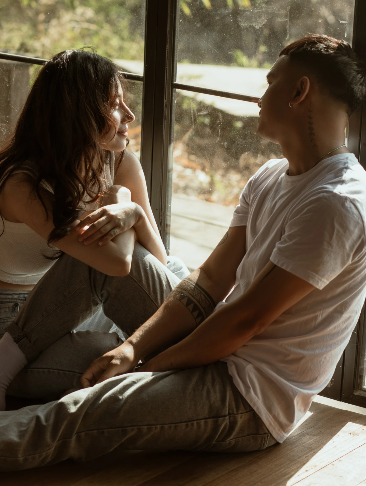 Pareja sentada junto a una ventana mostrando una conversación íntima que refleja la importancia de aprender a escuchar y detectar señales de mala comunicación.