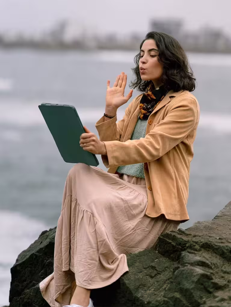Mujer realizando una videollamada frente al mar, imagen que representa las etapas de una relación a distancia y la conexión emocional a través de la pantalla.