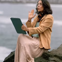 Mujer realizando una videollamada frente al mar, imagen que representa las etapas de una relación a distancia y la conexión emocional a través de la pantalla.